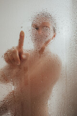 Fototapeta premium Cheerful woman drawing heart on condensed glass door