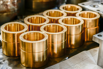 Bronze bushings for plunger hydraulic pumps, made on a cnc lathe, stand on a rack in a warehouse.