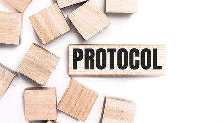 On a light background, wooden cubes and a wooden block with the text PROTOCOL. View from above