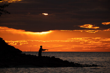 A man at sunset fishing