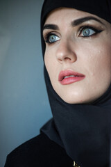  Muslim young woman on dark background wearing black hijab