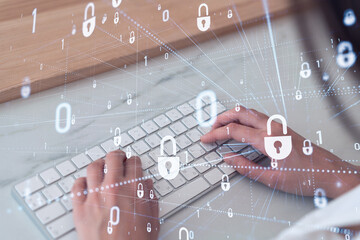 A woman programmer is typing a code on computer to protect a cyber security from hacker attacks and save clients confidential data. Padlock Hologram icons over the typing hands. Formal wear.