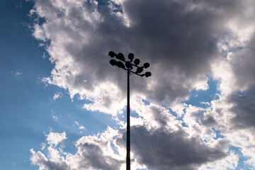 Light tower of a football stadium against a sunset and summer clouds and sky. Soccer stadium flashlights and evening.