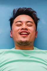 Fototapeta premium Portrait of young handsome Chinese man practicing yoga in the living room