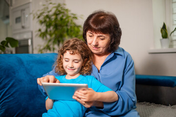 Grandmother with her granddaughter enthusiastically looking at the tablet screen