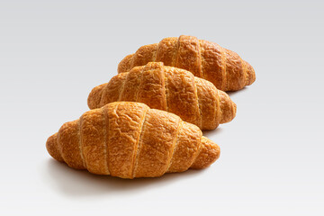 Three fresh French croissants in a row on a white background