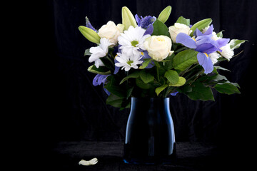 Funeral Bouquet purple White flowers, Sympathy and Condolence Concept on blackbackground with copy space.