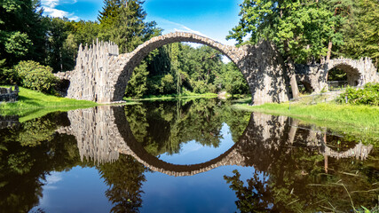 Rakotzbrücke Kromlau mit kreisförmiger Spiegelung im Wasser im Rhododendronpark