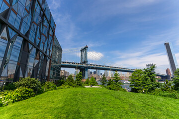 Manhattan Bridge stands beyond the East River from Lawn of the Brooklyn Bridge Park amidst Pandemic of COVID-19 on June 20, 2021 in New York City, USA.