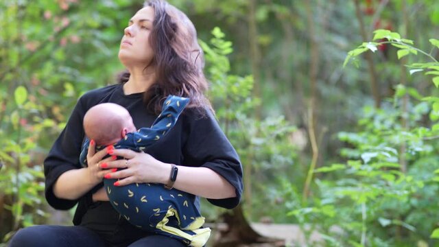 Young cute mom feeding baby breast milk in forest