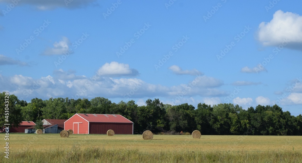 Sticker barn and hay bales in a field