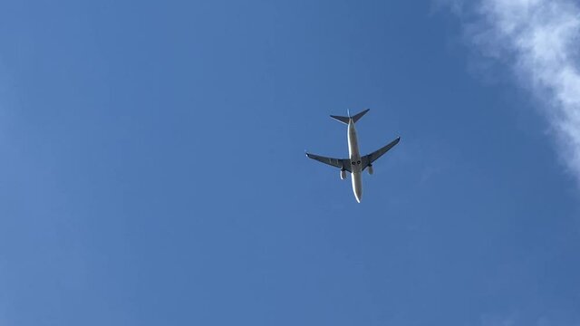 A commercial plane flying by, on a blue sky on the background