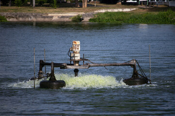 An electric aerator in a pond or river that uses a motor and a large propeller to spin.