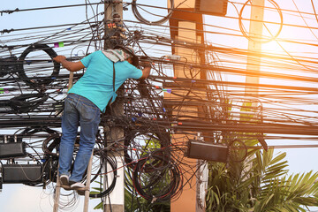 An electrician is climbing an electric pole to inspect and install wires without wearing protective...