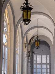 Antique and Huge Iron and Glass Chandeliers in a Public Corridor with Large Windows