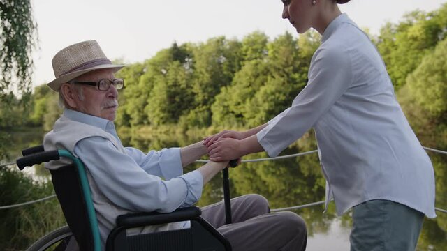 Man Sit In A Wheelchair And Nurse Huddle His Hands