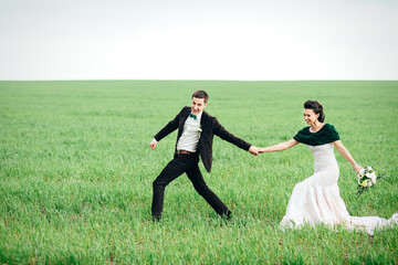 the groom in a brown suit and the bride in an ivory-colored dress on a green field