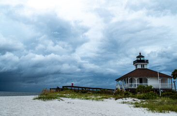 Port Boca Grande Lighthouse and Museum stand strong on Gasparilla Island as a tropical storm with black clouds loom of the coast in the Gulf of Mexico