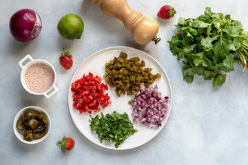Ingredients for making strawberry salsa. Strawberries, pickled jalapenos, sea salt, red onions, lime juice, chopped cilantro. Refreshing salad or appetizer, side dish or main course.