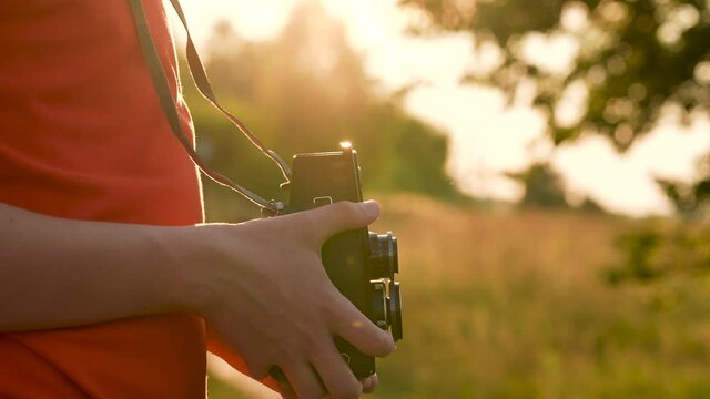 Close-up 4k stock video footage of young handsome teenage kid using old vintage analog photo or video camera outdoors on sunset sunny summer time