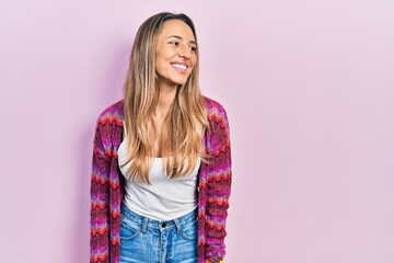 Beautiful hispanic woman wearing colored jacket looking away to side with smile on face, natural...