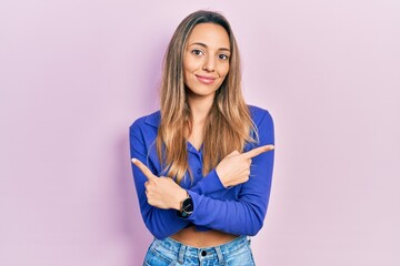 Fototapeta premium Beautiful hispanic woman wearing casual blue shirt pointing to both sides with fingers, different direction disagree