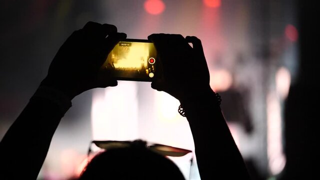 Silhouette main filme un concert dans un festival de musique