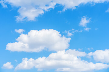Obraz na płótnie Canvas Bright blue sky with puffy white clouds, summer day sunlight