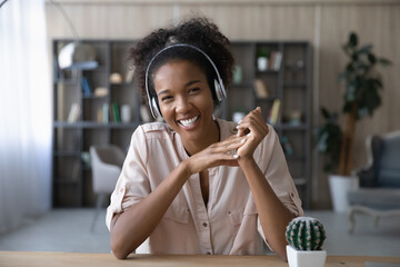 Portrait of smiling young African American woman in earphones look at camera have webcam digital virtual event. Happy ethnic female in headphones talk speak on video call. Communication concept. - Powered by Adobe