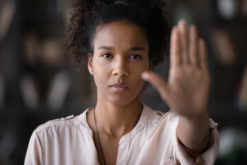Close up portrait of millennial African American woman show palm hand against domestic violence or abortion. Determined ethnic female make gesture protest against racial or gender discrimination.