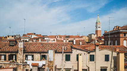 Fototapeta na wymiar San Marco bell tower over traditional Venetian houses under blue sky in Venice, Italy