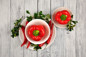 Red Bulgarian and Chili peppers on a gray wooden table.
