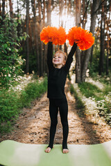 Beautiful smiling girl athlete professional, child cheerleader in a black suit raises his hands up...