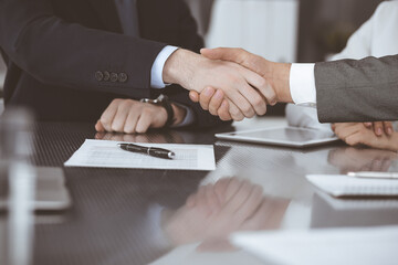 Handshake as successful negotiation ending, close-up. Unknown business people shaking hands after contract signing in modern office