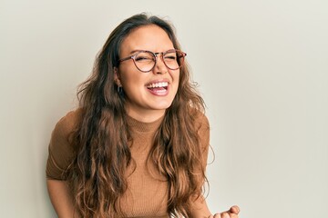 Fototapeta premium Young hispanic girl wearing casual clothes and glasses celebrating surprised and amazed for success with arms raised and eyes closed. winner concept.