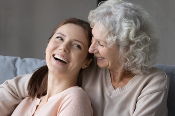 Close up of overjoyed mature 60s mom and grownup daughter hug and cuddle show love and care in family relations. Smiling old mother and adult child relax rest together. Motherhood, unity concept.