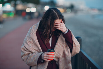 Fototapeta premium Young beautiful woman in coat and scarf with coffee cup outdoor