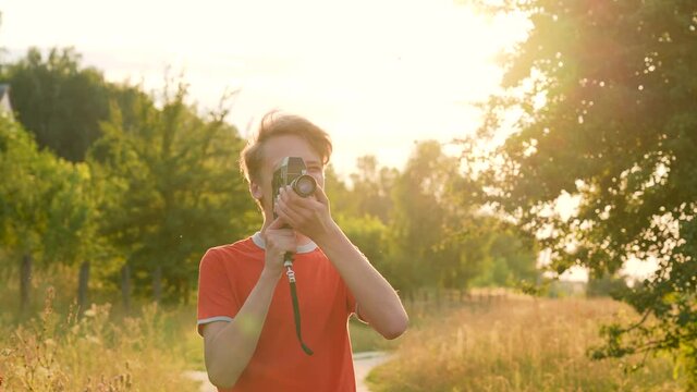 4k stock video footage of young handsome teenage kid using old vintage analog video camera outdoors on sunset sunny summer time