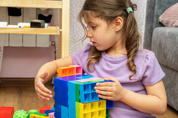 small kid girl playing with educational toy blocks constructor