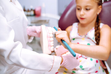 The little girl at the dentist's appointment. Inspection of the oral cavity and teeth in a child. Early prevention, oral hygiene and milk teeth care.