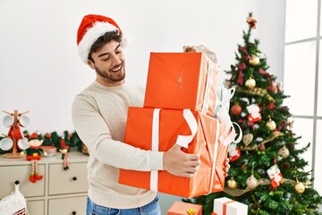 Obraz na płótnie Canvas Young hispanic man smiling happy holding gifts at home.