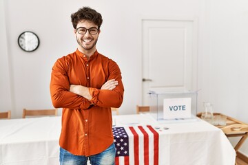 Hispanic man standing by election room happy face smiling with crossed arms looking at the camera....