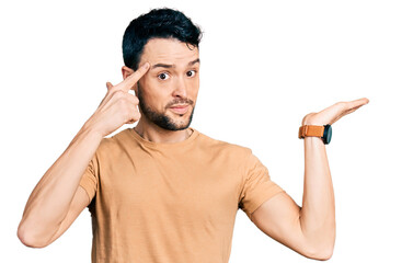 Hispanic man with beard wearing casual t shirt confused and annoyed with open palm showing copy...