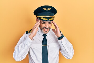 Handsome middle age man with grey hair wearing airplane pilot uniform with hand on head, headache because stress. suffering migraine.