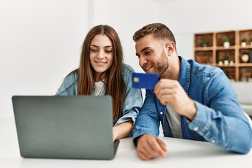 Young caucasian couple buying using laptop and credit card at home.