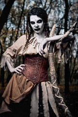 Halloween theme: ugly grim voodoo witch with staff. Portrait of evil sorceress in dark forest....
