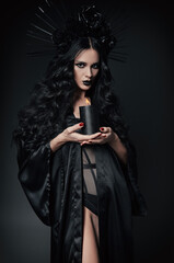 Halloween theme: sexy young witch dressed in black robe and headwear with roses and spikes....