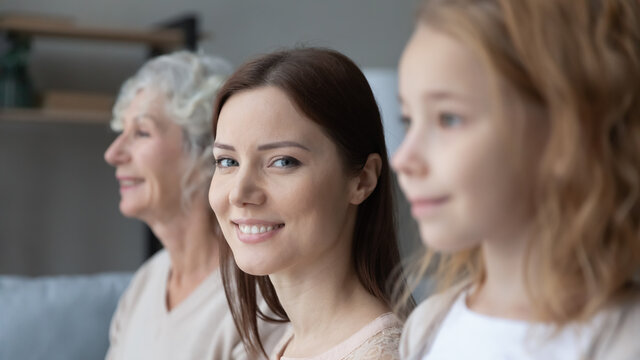 Close up portrait of young Caucasian woman pose with little teen daughter and old mother. Happy three generations of women look in distance visualize future together, show family unity bonding.