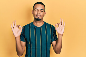 Young african american man wearing casual clothes relax and smiling with eyes closed doing meditation gesture with fingers. yoga concept.