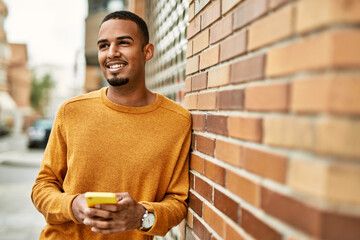 Young african american man smiling happy using smartphone at the city.